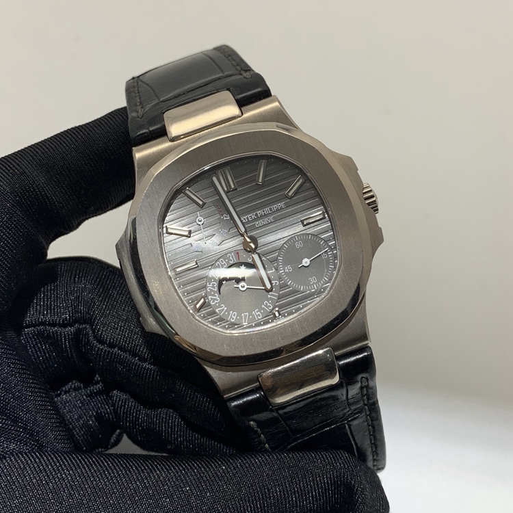 PATEK PHILIPPE 百达翡丽 NAUTILUS 运动系列，5712G-001。40毫米表径，18K白金表壳，深灰色面盘，覆荧光涂层金质立体时标，指针式日期显示、月相显示、动力储备显示功能，Cal.240 PS IRM C LU自动上弦机械机芯，动力储备48小时。专柜定价：318800元。 全套附件齐全。