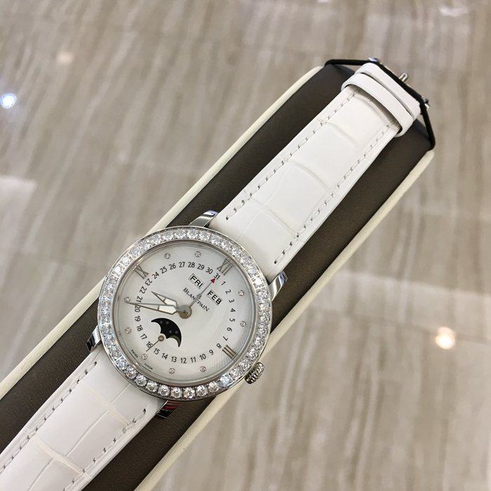 Blancpain 宝珀 WOMEN 女装系列，3663A-4654-55B。35毫米表径，精钢材质，透明表底，表圈镶嵌40壳明亮式钻石，约1.95克拉。珍珠贝母面镶嵌美钻，中心指针式日期显示，视窗式月份、星期、月相显示，六时位小秒针。自产 Cal.6763 自动上弦机械机芯，动力储备100小时。专柜定价148500元。 未使用品全套附件齐全。
