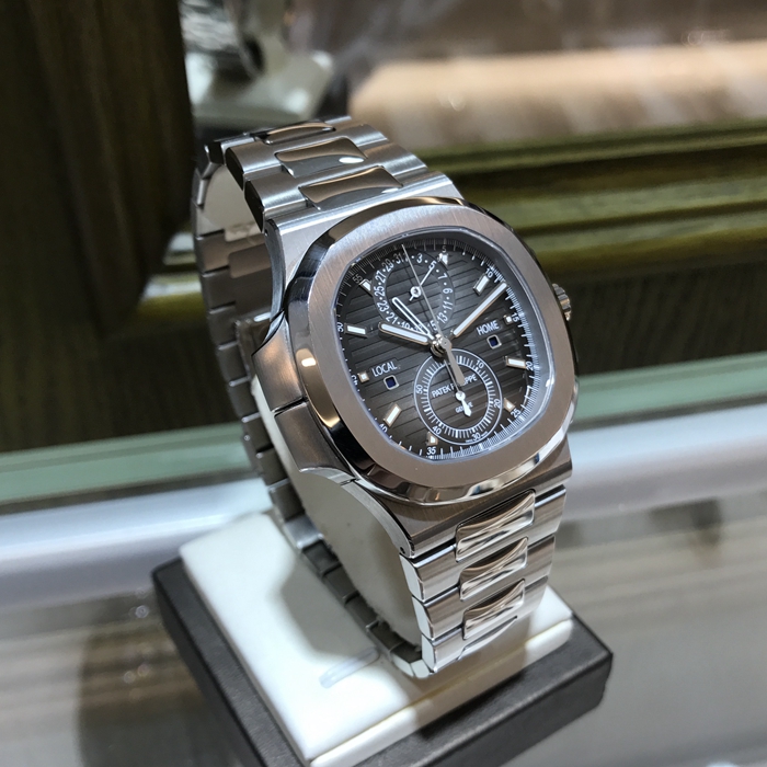 PATEK PHILIPPE 百达翡丽  NAUTILUS 运动系列，旅行家计时码表 5990/1A-001。40.5毫米表径，精钢表壳，黑色表盘带有从内到外的明暗渐变效果，搭配熟悉的NAUTILUS水平浮雕图案，并点缀10枚18K白金荧光立体时标，6点位置为60分钟累积计时器，12点位置为针式日期显示，两个独立昼/夜显示窗口，分别标示“LOCAL（当地）”和HOME（原居地）“，以显示不同时区的昼夜时间，有了这项功能，出门在外的人就不会在深夜无意间电话影响正在远方休息的家人。走遍全球，但始终不忘本源（家）。自产CH 28-520 C FUS自动上弦机械机芯，动力储备45-55小时。专柜定价：401400元。 全套附件齐全。