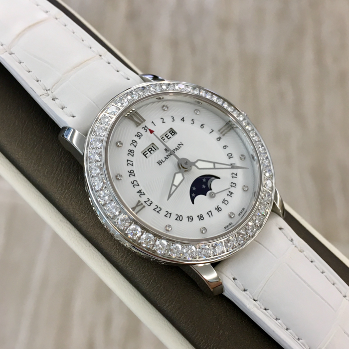Blancpain 宝珀 WOMEN 女装系列，3663A-4654-55B。35毫米表径，精钢材质，透明表底，表圈镶嵌40壳明亮式钻石，约1.95克拉。珍珠贝母面镶嵌美钻，中心指针式日期显示，视窗式月份、星期、月相显示，六时位小秒针。自产 Cal.6763 自动上弦机械机芯，动力储备100小时。专柜定价148500元。 未使用品全套附件齐全。