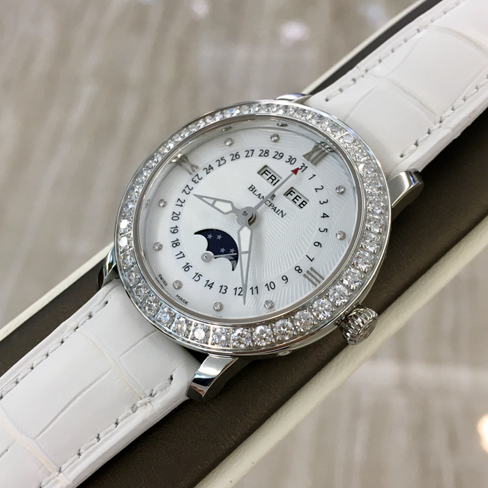 Blancpain 宝珀 WOMEN 女装系列，3663A-4654-55B。35毫米表径，精钢材质，透明表底，表圈镶嵌40壳明亮式钻石，约1.95克拉。珍珠贝母面镶嵌美钻，中心指针式日期显示，视窗式月份、星期、月相显示，六时位小秒针。自产 Cal.6763 自动上弦机械机芯，动力储备100小时。专柜定价148500元。 未使用品全套附件齐全。