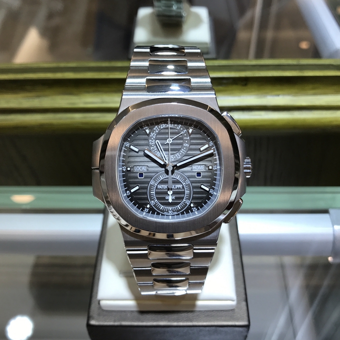 PATEK PHILIPPE 百达翡丽  NAUTILUS 运动系列，旅行家计时码表 5990/1A-001。40.5毫米表径，精钢表壳，黑色表盘带有从内到外的明暗渐变效果，搭配熟悉的NAUTILUS水平浮雕图案，并点缀10枚18K白金荧光立体时标，6点位置为60分钟累积计时器，12点位置为针式日期显示，两个独立昼/夜显示窗口，分别标示“LOCAL（当地）”和HOME（原居地）“，以显示不同时区的昼夜时间，有了这项功能，出门在外的人就不会在深夜无意间电话影响正在远方休息的家人。走遍全球，但始终不忘本源（家）。自产CH 28-520 C FUS自动上弦机械机芯，动力储备45-55小时。专柜定价：401400元。 全套附件齐全。