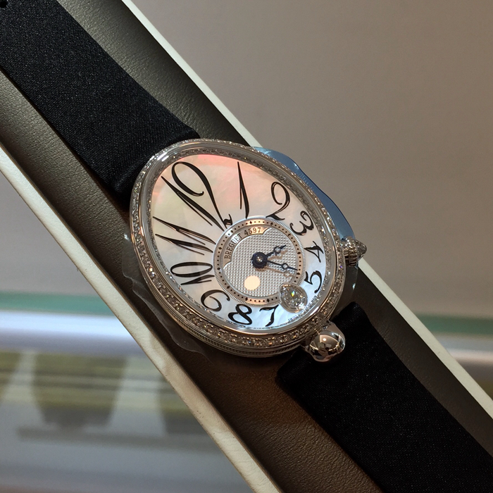 Breguet 宝玑 Reine de Naples 那不勒斯皇后系列，8918BB/58/864/D00D。18K白金鹅卵形表壳，36.5 x 28.45毫米表径。表壳外缘饰有钱币纹。表圈和表壳周围镶嵌117颗明亮式切割钻石（约0.99克拉）。表冠处镶有一颗梨形钻石（约0.26克拉）。蓝宝石水晶底盖。表盘为大溪地天然白色珍珠母贝，采用玑镂刻花处理。具有独立编号与Breguet隐形签名。偏心刻度环位于6点位置，采用宝玑阿拉伯数字时符。6点位镶嵌梨形钻石（约0.09克拉）。经典的蓝钢宝玑指针。金质折叠表扣，镶嵌26颗明亮式切割钻石（约0.12克拉）。537/3自动上链机芯，动力储备45小时。