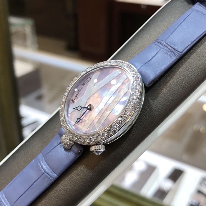 Breguet 宝玑 Reine de Naples 那不勒斯皇后系列 ，9818BB/5V/922/DD0D。32.7x27.3毫米表径，18K白金镶钻表壳，鹅卵形表壳，表壳外缘饰有钱币纹。表圈和表耳上镶嵌64颗明亮式切割钻石（约1.654克拉）。表冠处镶有一颗梨形钻石（约0.15克拉）。淡紫色珍珠贝母面，镌刻独立编号和Breguet隐形签名。6点位置设有偏心小时刻度环，采用罗马数字时标，镶刻白色天然珍珠母贝雕饰。宝玑经典针尖镂空式蓝钢指针。自动上链机芯，自动上弦机械机芯，动力储备38小时。专柜定价：291300元。 未使用品全套附件齐全。