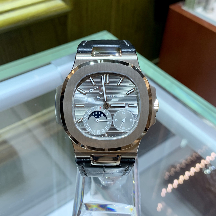 PATEK PHILIPPE 百达翡丽 NAUTILUS 运动系列，5712G-001。40毫米表径，18K白金表壳，水平横纹浮雕图案的表盘，覆荧光涂层金质立体时标，指针式日期显示，动力储备显示、月相显示功能，240 PS IRM C LU自动上弦机械机芯，动力储备48小时，专柜定价：318800元。 全套附件齐全。