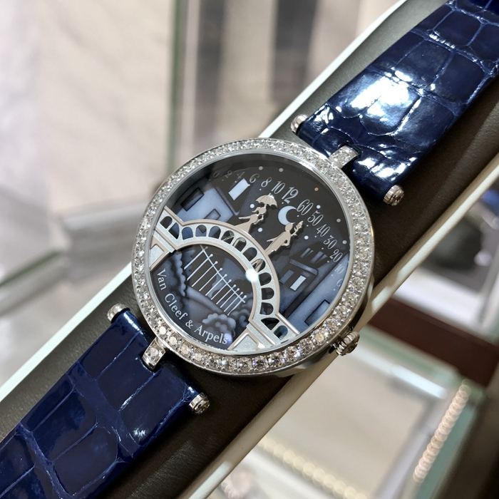 Van Cleef & Arpels 梵克雅宝 诗意复杂功能腕表系列， VCARN9VI00。梵克雅宝恋人之桥腕表的技术和创意名动一方，在表盘中，男孩显示分钟，女孩显示小时，表盘成为一对恋人的相遇地点，在每天23：55的时候女孩终于轻轻一跃，扑到男孩怀中，深情拥吻5分钟，这款腕表堪称机械与爱情的完美结合。 未使用品全套附件齐全。