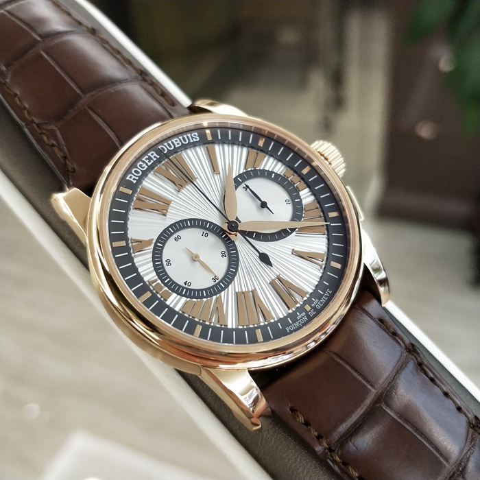 RogerDubuis 罗杰杜彼 Hommage 致敬系列，RDDBHO0569。42毫米表径。18K玫瑰金表壳， 手工玑镂饰纹表盘，腕表采用造型大胆的长方形按把和布满凹槽线条的表冠，展现出鲜明的阳刚性格，却又以优美的圆弧曲线以及长秒针的叶形尾端带来柔和的色彩。位于3点钟和9点钟位置的蜗形纹计时圈有力地见证着传统制表同样能够符合现代精确计时需求的事实。蓝宝石水晶玻璃表镜。RD680 自动上弦机械机芯，搭载微型摆陀。动力储备52小时。 全套附件齐全。