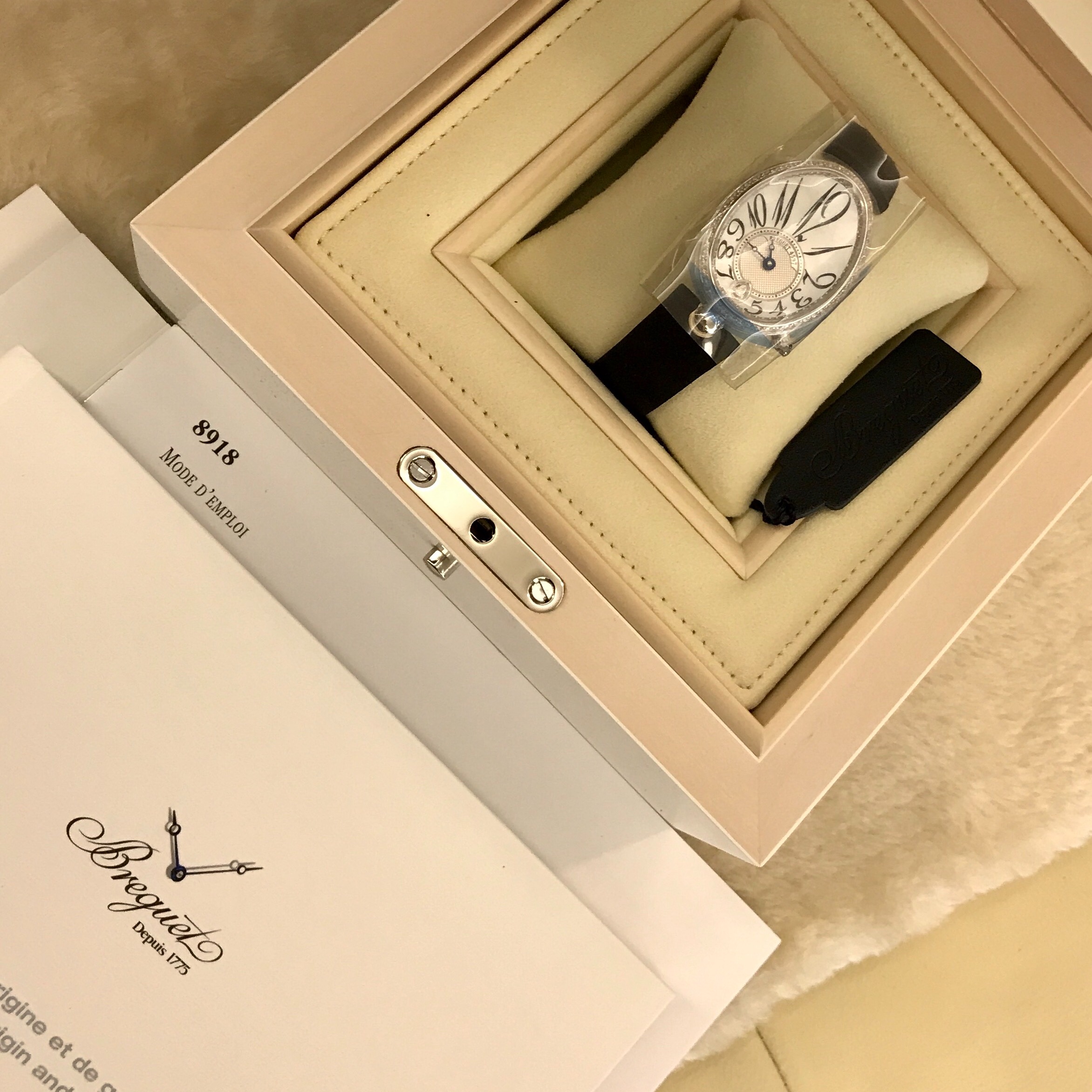 Breguet 宝玑 Reine de Naples 那不勒斯皇后系列，8918BB/58/864/D00D。18K白金鹅卵形表壳，36.5 x 28.45毫米表径。表壳外缘饰有钱币纹。表圈和表壳周围镶嵌117颗明亮式切割钻石（约0.99克拉）。表冠处镶有一颗梨形钻石（约0.26克拉）。蓝宝石水晶底盖。表盘为大溪地天然白色珍珠母贝，采用玑镂刻花处理。具有独立编号与Breguet隐形签名。偏心刻度环位于6点位置，采用宝玑阿拉伯数字时符。6点位镶嵌梨形钻石（约0.09克拉）。经典的蓝钢宝玑指针。金质折叠表扣，镶嵌26颗明亮式切割钻石（约0.12克拉）。537/3自动上链机芯，动力储备45小时。