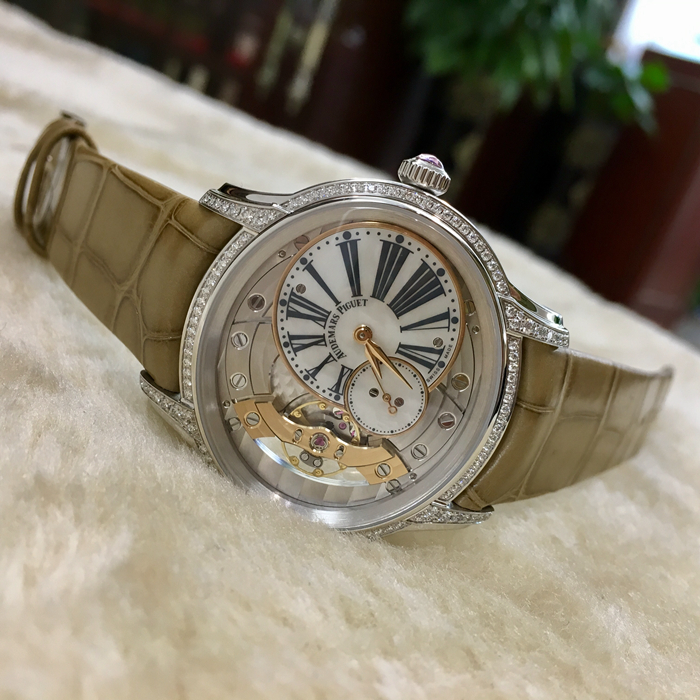 Audemars Piguet 爱彼 Millenary千禧系列，77247BC.ZZ.A813CR.01，39.5*35.5毫米表径。手动上链腕表，搭配小秒针。18K白金表壳搭配镶钻表圈和表耳及镶嵌一颗粉红色凸面蓝宝石的表冠，116颗明亮型切割美钻，总重约0.60克拉（表圈和表耳）。白色珍珠贝母偏心式圆盘，小秒盘，炭灰色印制罗马数字，玫瑰金指针。方形大鳞片米黄色鳄鱼皮表带。5201型手动上链自产机芯，动力储备54小时。专柜定价：230000元。