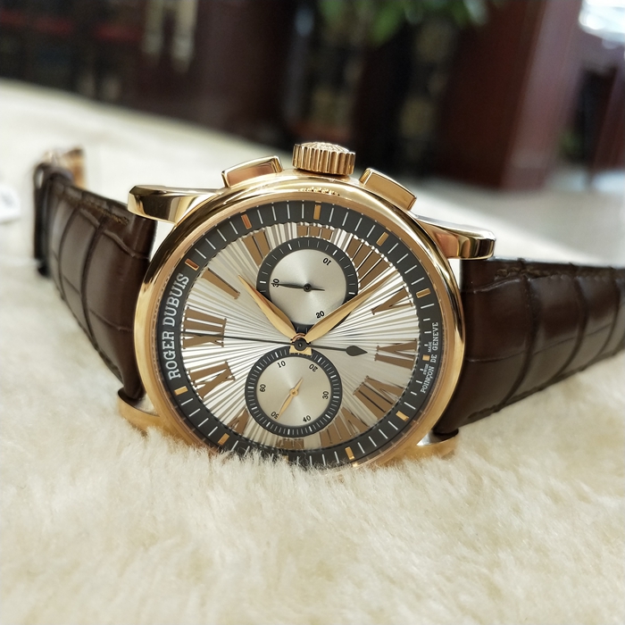 RogerDubuis 罗杰杜彼 Hommage 致敬系列，RDDBHO0569。42毫米表径。18K玫瑰金表壳， 手工玑镂饰纹表盘，腕表采用造型大胆的长方形按把和布满凹槽线条的表冠，展现出鲜明的阳刚性格，却又以优美的圆弧曲线以及长秒针的叶形尾端带来柔和的色彩。位于3点钟和9点钟位置的蜗形纹计时圈有力地见证着传统制表同样能够符合现代精确计时需求的事实。蓝宝石水晶玻璃表镜。RD680 自动上弦机械机芯，搭载微型摆陀。动力储备52小时。 全套附件齐全。