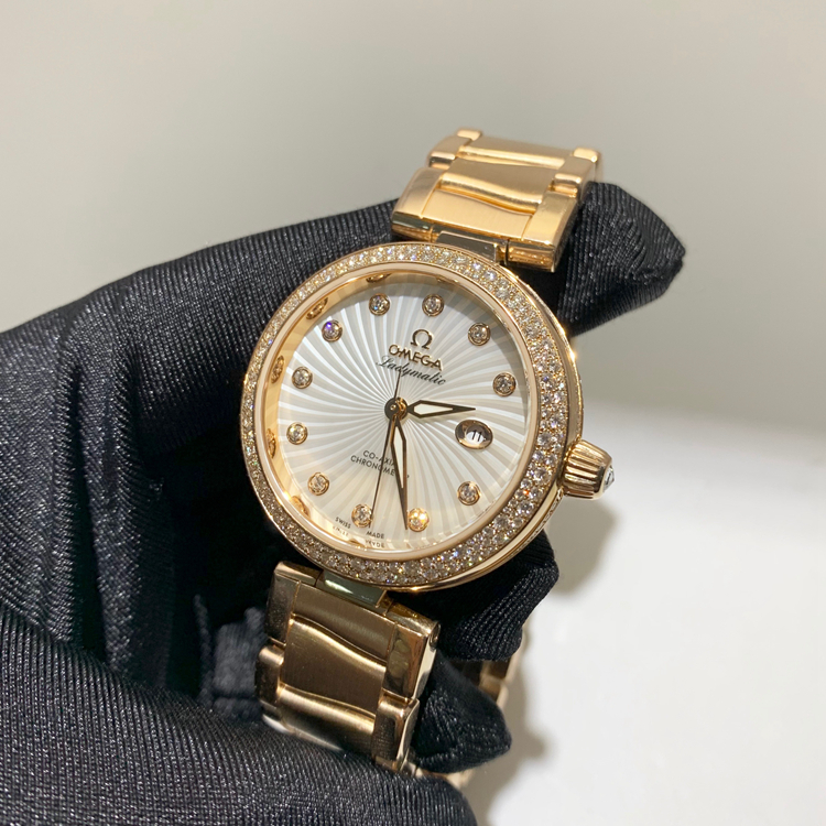 Omega 欧米茄 碟飞系列，425.65.34.20.55.003。34毫米表径，18K玫瑰金原钻表壳，刻钻珍珠贝母面盘，日期显示功能，自产Cal.8521自动上弦机械机芯，动力储备50小时。专柜定价：313100元。 单表无附件。