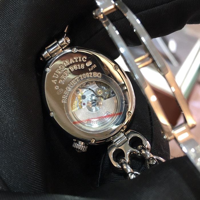 Breguet 宝玑 Reine de Naples 那不勒斯皇后系列 ，9818BB/5V/J51 DDD0。32.7x27.3毫米表径，18K白金镶钻表壳，鹅卵形表壳，表壳外缘饰有钱币纹。表圈和表耳上镶嵌64颗明亮式切割钻石（约1.654克拉），表冠处镶有一颗梨形钻石（约0.15克拉）。淡紫色珍珠贝母面，镌刻独立编号和Breguet隐形签名。6点位置设有偏心小时刻度环，采用罗马数字时标，镶刻白色天然珍珠母贝雕饰。宝玑经典针尖镂空式蓝钢指针。自动上弦机械机芯，动力储备38小时。 全套附件齐全。