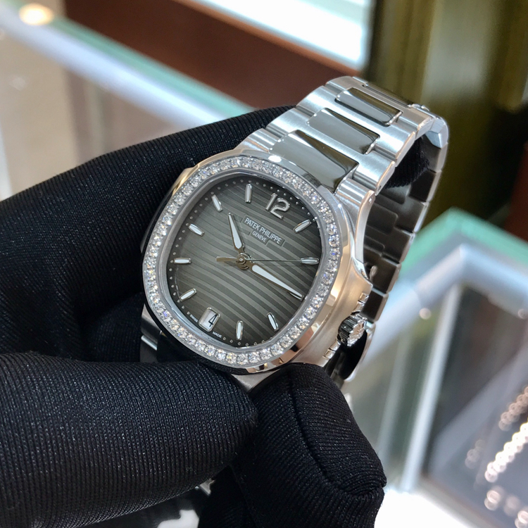 PATEK PHILIPPE 百达翡丽 NAUTILUS 运动系列，7018/1A-011。33.6毫米表径，精钢表壳，镶嵌50颗钻石，约0.71克拉，炭灰色饰有水平横纹浮雕图案面盘，金质立体字块，荧光时标，中心大秒针，6点位置视窗式日期显示，Cal.324 S C自动上弦机械机芯，动力储备45小时。专柜定价：247700元。 未使用品单表附保卡。