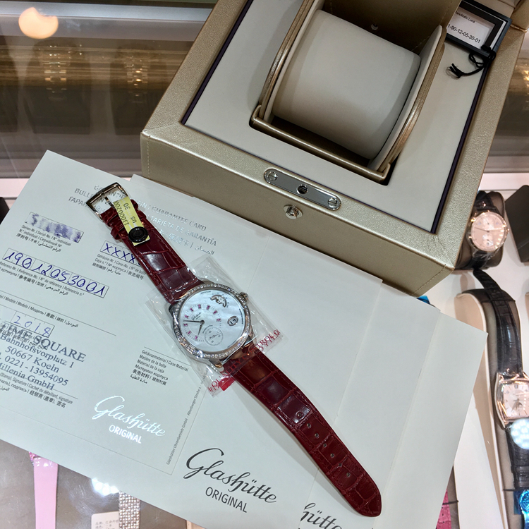 Glashutte 格拉苏蒂原创 女表90系列，1-90-12-05-30-01。精钢39.4毫米表径，原装镶钻，镶嵌 64 颗钻石(总重约 0.95ct，VVS), 表冠镶嵌红宝石 (约 0.022ct, VVS)。珍珠母贝白色表盘，18颗红宝石（约0.045克拉，VVS）。金质偏心盘指针，大日历显示，月相显示，自动上弦机械机芯，动力储备42小时，全球限量50枚。专柜定价：154000元。 未使用品全套附件齐全。