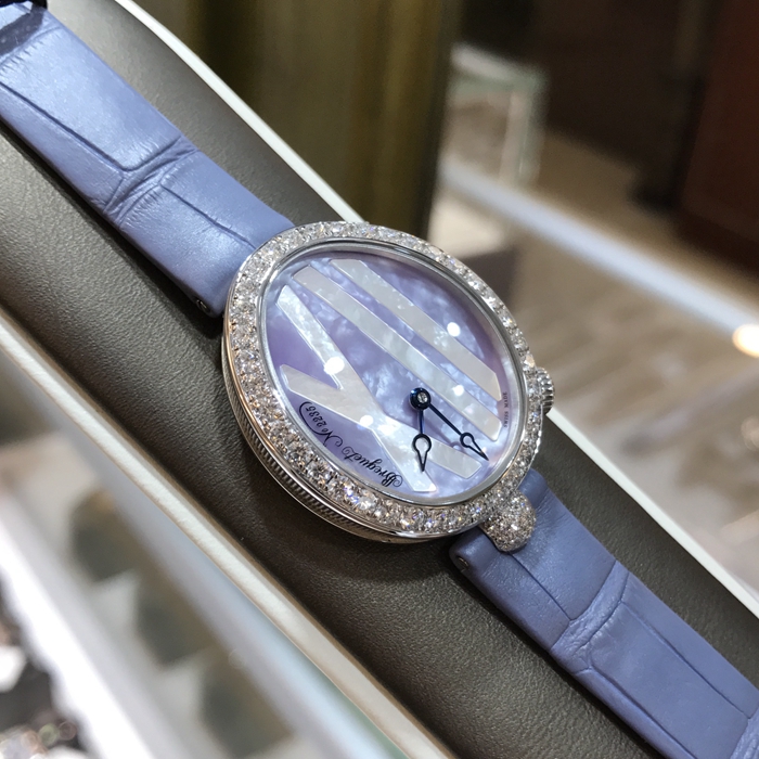 Breguet 宝玑 Reine de Naples 那不勒斯皇后系列 ，9818BB/5V/922/DD0D。32.7x27.3毫米表径，18K白金镶钻表壳，鹅卵形表壳，表壳外缘饰有钱币纹。表圈和表耳上镶嵌64颗明亮式切割钻石（约1.654克拉）。表冠处镶有一颗梨形钻石（约0.15克拉）。淡紫色珍珠贝母面，镌刻独立编号和Breguet隐形签名。6点位置设有偏心小时刻度环，采用罗马数字时标，镶刻白色天然珍珠母贝雕饰。宝玑经典针尖镂空式蓝钢指针。自动上链机芯，自动上弦机械机芯，动力储备38小时。专柜定价：291300元。 未使用品全套附件齐全。