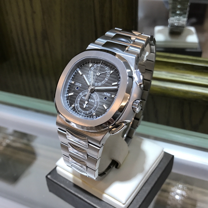 PATEK PHILIPPE 百达翡丽  NAUTILUS 运动系列，旅行家计时码表 5990/1A-001。40.5毫米表径，精钢表壳，黑色表盘带有从内到外的明暗渐变效果，搭配熟悉的NAUTILUS水平浮雕图案，并点缀10枚18K白金荧光立体时标，6点位置为60分钟累积计时器，12点位置为针式日期显示，两个独立昼/夜显示窗口，分别标示“LOCAL（当地）”和HOME（原居地）“，以显示不同时区的昼夜时间，有了这项功能，出门在外的人就不会在深夜无意间电话影响正在远方休息的家人。走遍全球，但始终不忘本源（家）。自产CH 28-520 C FUS自动上弦机械机芯，动力储备45-55小时。专柜定价：401400元。 全套附件齐全。