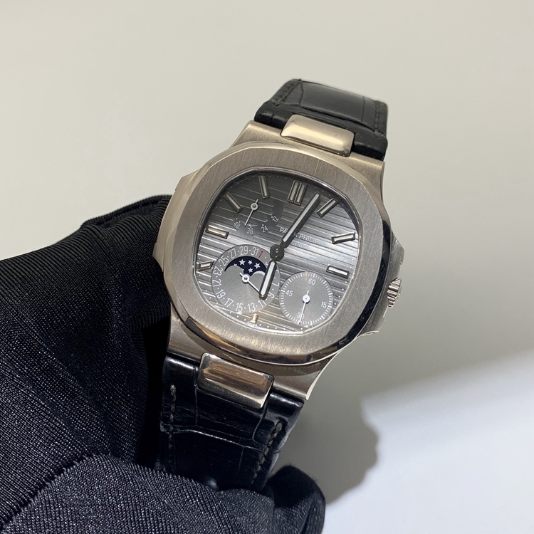 PATEK PHILIPPE 百达翡丽 NAUTILUS 运动系列，5712G-001。40毫米表径，18K白金表壳，深灰色面盘，覆荧光涂层金质立体时标，指针式日期显示、月相显示、动力储备显示功能，Cal.240 PS IRM C LU自动上弦机械机芯，动力储备48小时。专柜定价：318800元。 全套附件齐全。