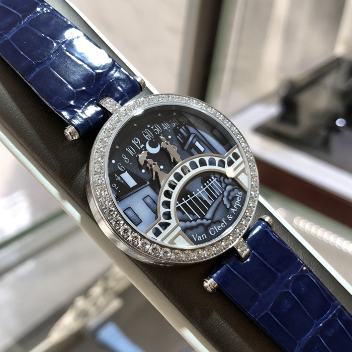 Van Cleef & Arpels 梵克雅宝 诗意复杂功能腕表系列， VCARN9VI00。梵克雅宝恋人之桥腕表的技术和创意名动一方，在表盘中，男孩显示分钟，女孩显示小时，表盘成为一对恋人的相遇地点，在每天23：55的时候女孩终于轻轻一跃，扑到男孩怀中，深情拥吻5分钟，这款腕表堪称机械与爱情的完美结合。 未使用品全套附件齐全。