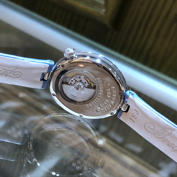 Breguet 宝玑 Reine de Naples 那不勒斯皇后系列 ，9818BB/5V/922/DD0D。32.7x27.3毫米表径，18K白金镶钻表壳，鹅卵形表壳，表壳外缘饰有钱币纹。表圈和表耳上镶嵌64颗明亮式切割钻石（约1.654克拉）。表冠处镶有一颗梨形钻石（约0.15克拉）。淡紫色珍珠贝母面，镌刻独立编号和Breguet隐形签名。6点位置设有偏心小时刻度环，采用罗马数字时标，镶刻白色天然珍珠母贝雕饰。宝玑经典针尖镂空式蓝钢指针。自动上链机芯，自动上弦机械机芯，动力储备38小时。专柜定价：291300元。 未使用品全套附件齐全。